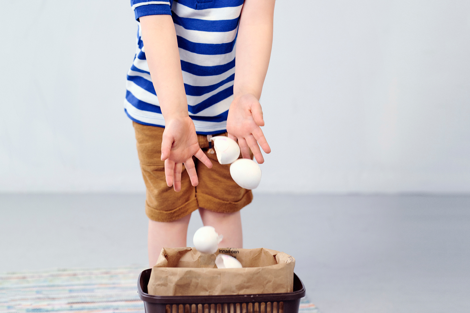 Barn som kastar äggskal i en matavfallspåse